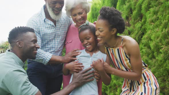 Portrait of happy african american family embracing and smiling in garden