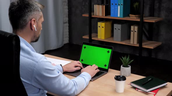 Man Stock Trader Broker Works for Laptop with Green Screen Typing on Keyboard