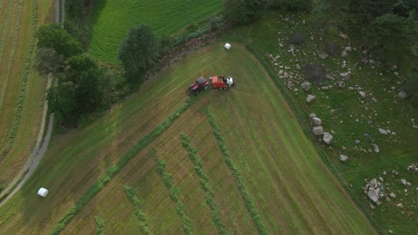 Tractor with baling machine making silage bales on farmland, Scandinavia