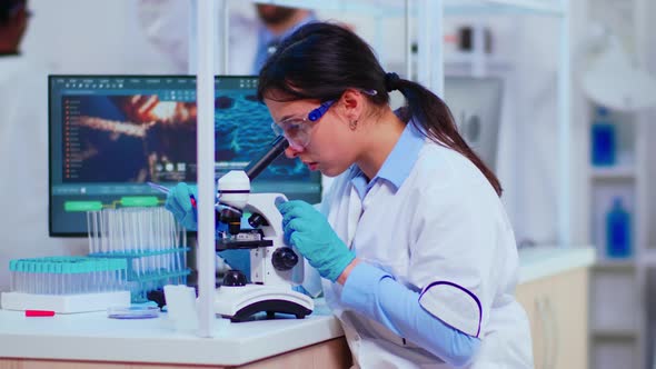 Scientist Woman with Microscope Examining Samples and Liquid