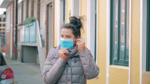 Woman in City Street Putting on Face Protective Mask