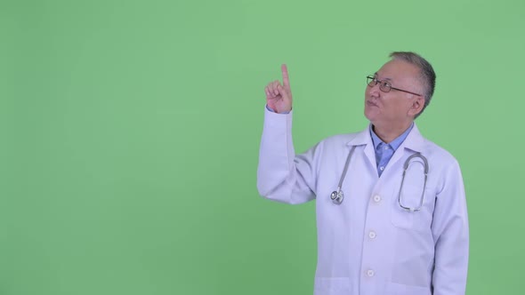 Happy Mature Japanese Man Doctor Thinking and Pointing Up