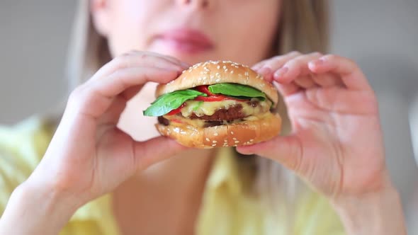 Woman eating burger on a table in kitchen in home