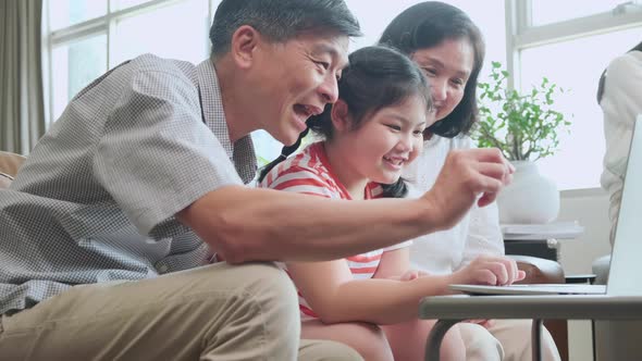 grand mother grandfather teach little child granddaughter using laptop sit on sofa, happy relation