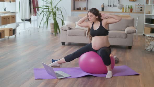 Young Pregnant Woman Doing Stretching in the Living Room at Home