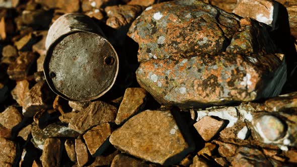 Rusty Destroyed Metal Barrel on Beach Rocks