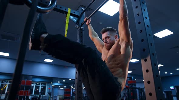 Strong man doing pull ups in gym. Male athlete with fit torso doing pull ups indoor