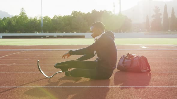 Disabled mixed race man with prosthetic legs stretching before a race