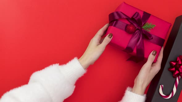 Female hands fold christmas gifts on the red background - Stop motion animation