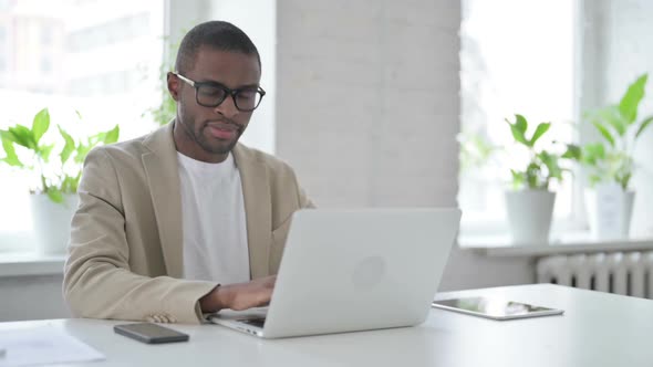 African Man Shaking Head As No Sign While Using Laptop in Office