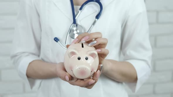 Doctor's hands with a piggy bank.