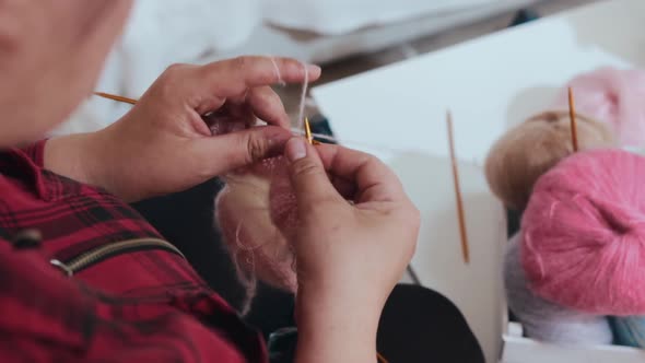 A Woman Knits Puppy Clothes with Knitting Needles