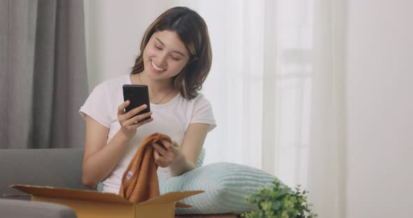 Happy Beautiful Asian Woman Opening Box With Ordered Clothes And Take A Picture.