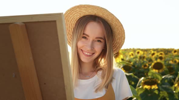 A Woman is Standing in a Field of Sunflowers and Drawing a Picture