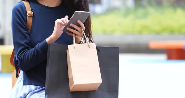 Woman use of mobile phone and hold with shopping bag