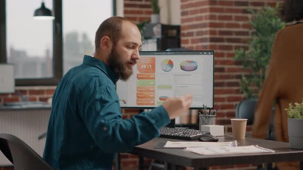 Employee Working with Rate Data Charts on Computer at Desk