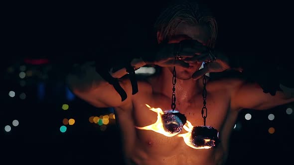 Young Blond Male Holds Two Pois Hanging on Chains Raises Them Then Lowers Them