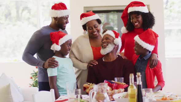 African american family in santa hats talking and smiling together at home