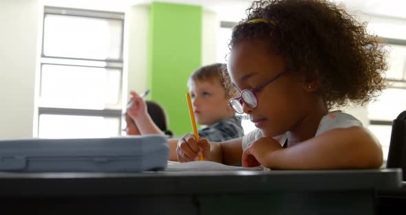 Side view of African american schoolgirl studying at desk in classroom at school 4k