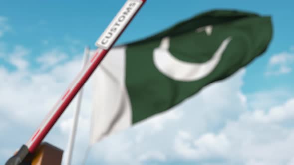 Barrier Gate with CUSTOMS Sign Being Closed Near Flag of Pakistan alt