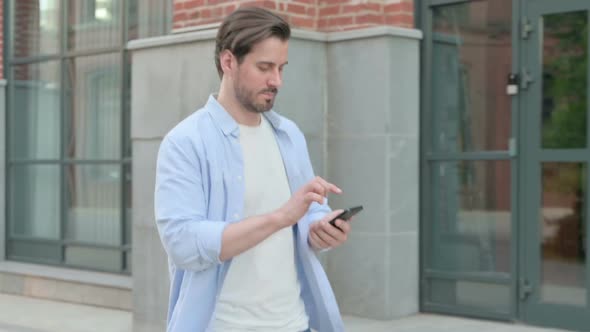 Man Talking on Phone While Walking in Street