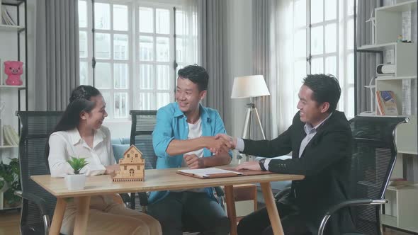 Man Sitting With A Woman And House Purchase Contract Paper Shaking Hand With A Real Estate Agent