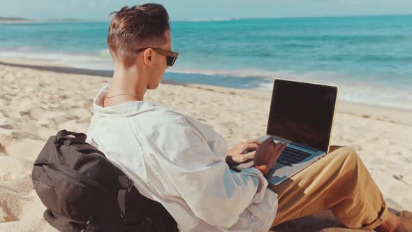 Behind Shoulder Shot of Young Professional Freelancer Lay on Beach Barefoot