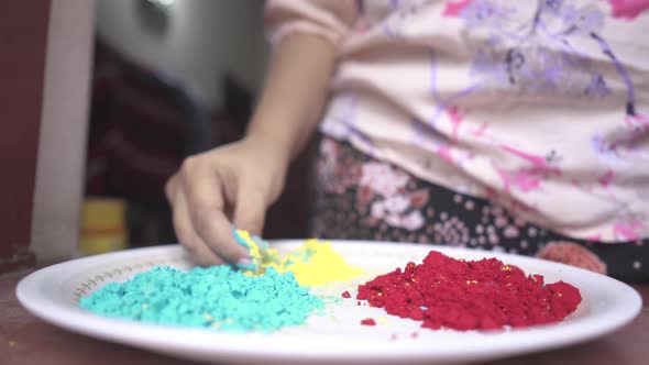 Hand of girl playing with color powders on plate inside home due to coronavirus lockdown, slow motio