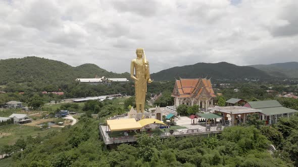 Wat Khao Noi temple surrounded by nature, Giant golden Buddha in Hua Hin. Aerial Orbiting shot