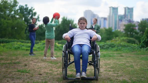 Wide Shot Depressed Disabled Girl in Wheelchair Looking at Camera with Sad Facial Expression As