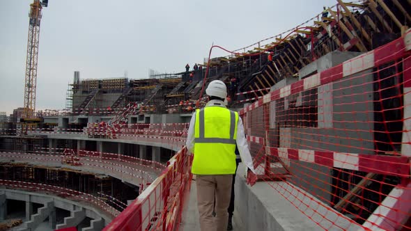Engineer Walks Along Future Spectator Places at Sports Arena