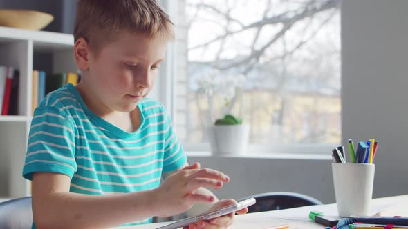 Boy is Doing  Homework at the Table. Cute Child is Learning at Home.