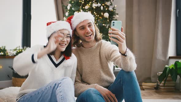 Mixed Race Pair Smiling Talking By Online Video Call Using Smartphone Sitting Against Decorated