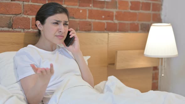 Angry Young Indian Woman Talking on Phone in Bed