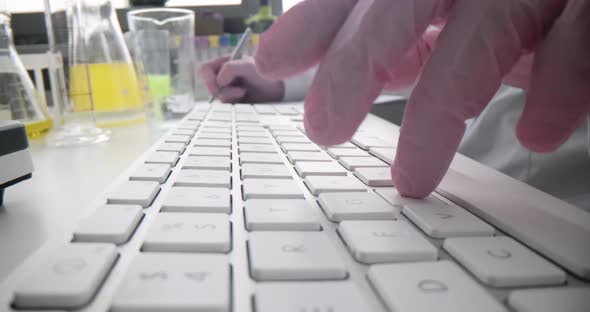 A Chemist in a Laboratory is Typing on a Computer Keyboard alt