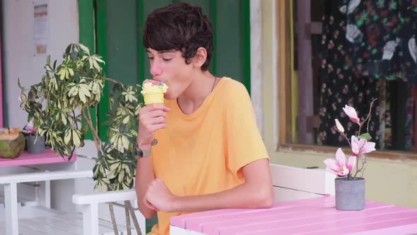 Close up of boy looking around then eating lemon sprinkled ice cream