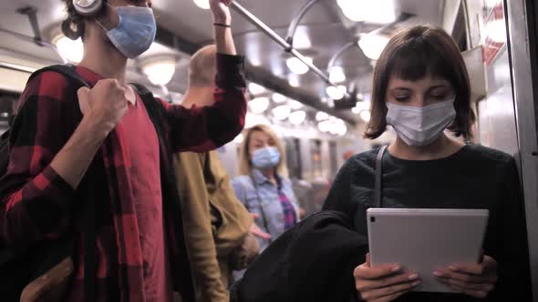 Young Masked Woman Using Tablet in Metro Car