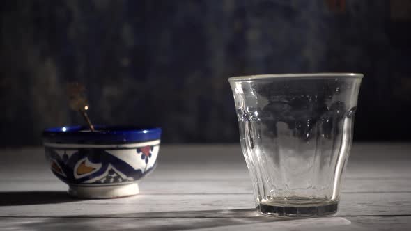 Cinemagraph of closeup of tea pouring into a glass with Moroccan tea set and mint.