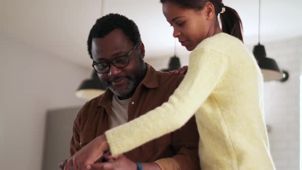 Cheerful daughter showing someone at phone to her father