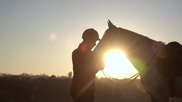 Horsewoman Kisses a Horse at Sunset