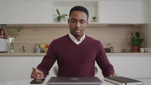 An African American 20s Adult Man Walks in the Frame Opens the Laptop and Gets to Work