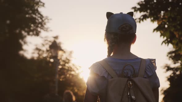 A Child with a Backpack Is Standing in the Park