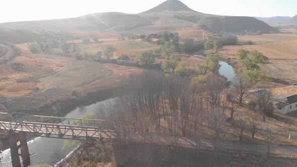 aerial tracking a mountain biker crossing a steel bridge on a gravel road