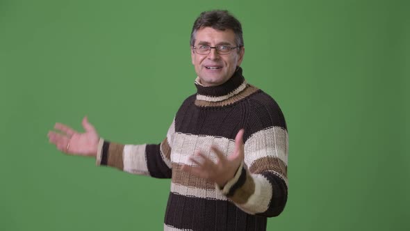 Mature Handsome Man Wearing Turtleneck Sweater Against Green Background