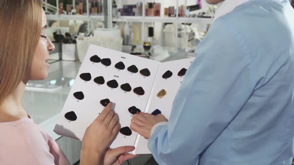 Rearview Close Up of a Woman and Her Hairdresser Examining Hair Dye Color Chart