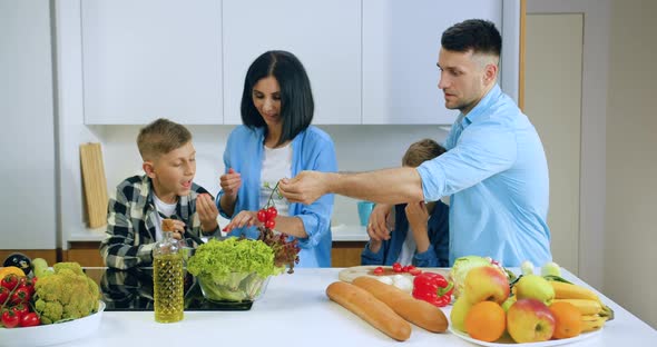 Family with Children Preparing Together Fresh Healthy Dinner while Standing Near Kitchen Table