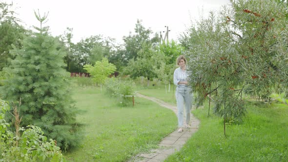 Carefree and easygoing woman walking at city park pathway or garden, carry notebook