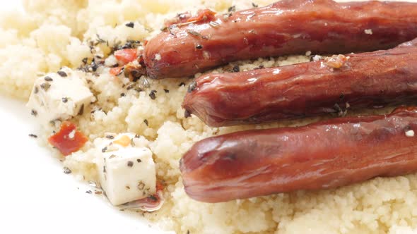 Meat sausages cheese cubes and couscous served on the plate slow tilt close-up 4K 3840X2160 30fps UH