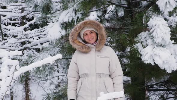 Female Video Portrait Slowmotion Shooting a Woman in a Winter Forest Smiles Looking at the Camera