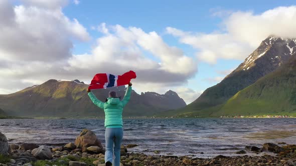 Woman with a Waving Flag of Norway on the Background of Nature